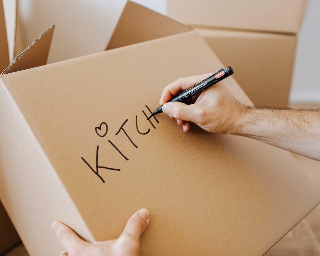Person writing kitchen on a packing box