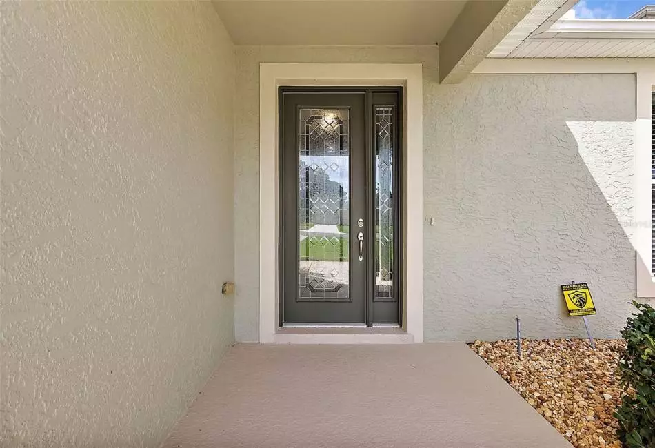 Front Door Entry with Stunning Lead Glass Door & Side Light. Gutters surround the outside of the house.