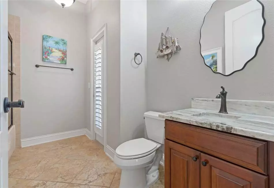 The Pool/Guest Bath has granite counters and stamped ceramic tile flooring with a bath and shower combination.
