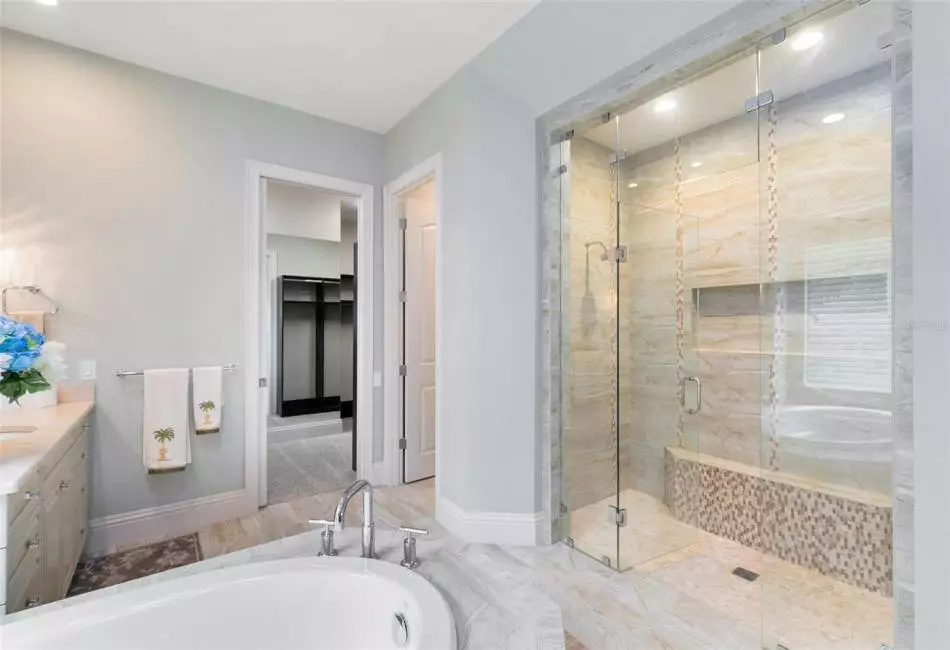 A large, dual headed walk-in shower features a half bench seat.
