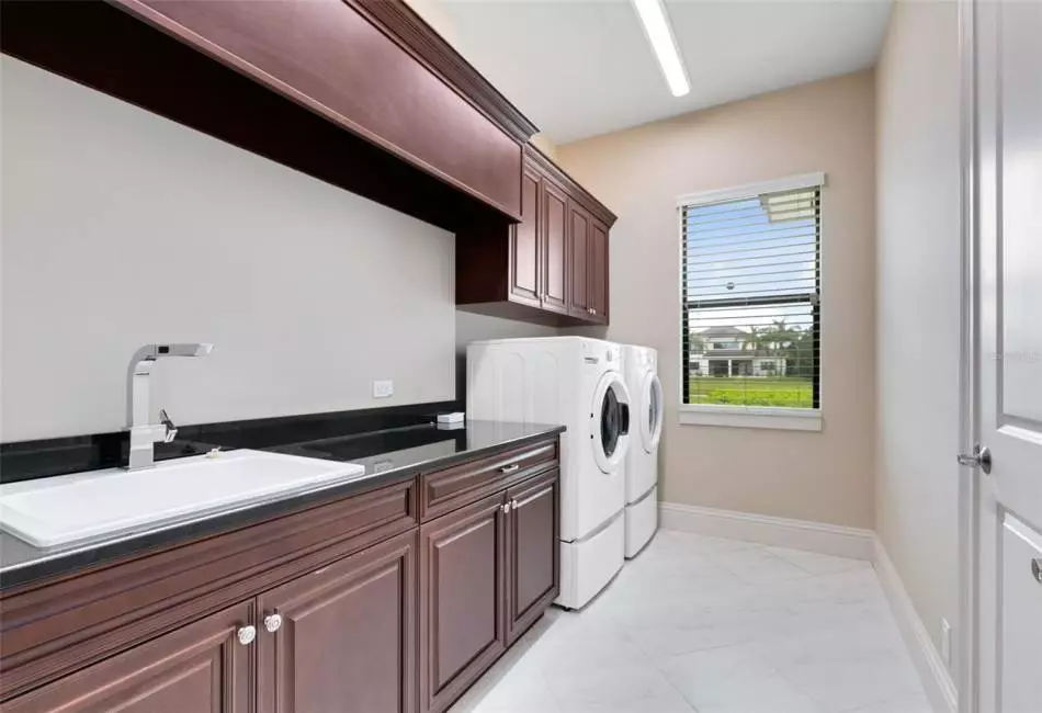 A large laundry room features a sink, cabinets and counter space.