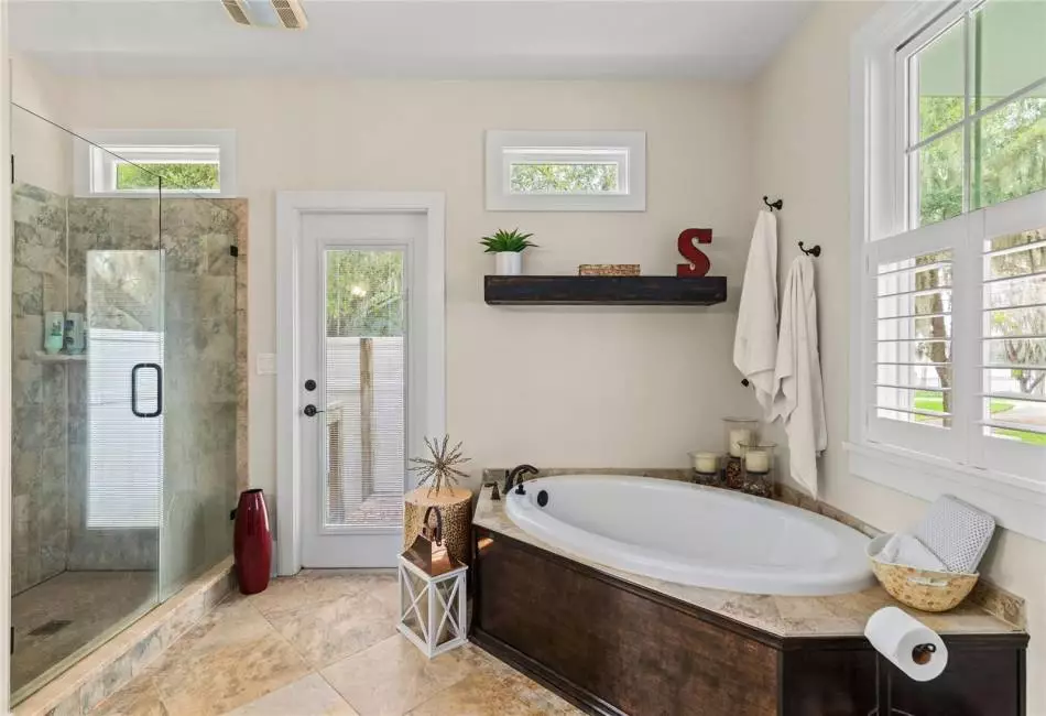 Primary Bathroom with stand up shower and oversized soaking tub. Views of Lake Victoria. Connected to outside shower via side door.