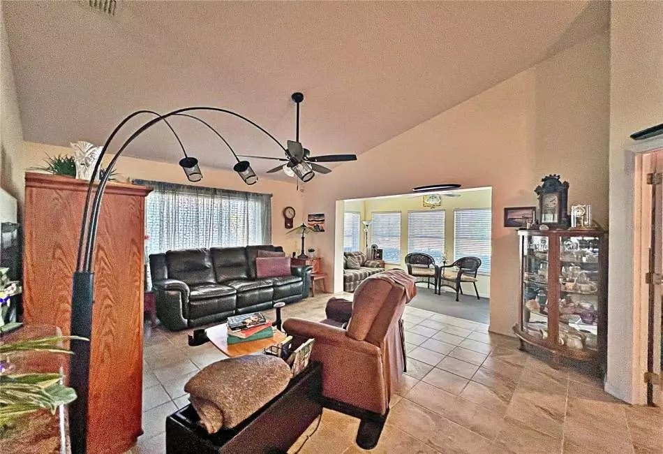 Living room with view of enclosed rear lanai, ceramic tile flooring, high ceilings