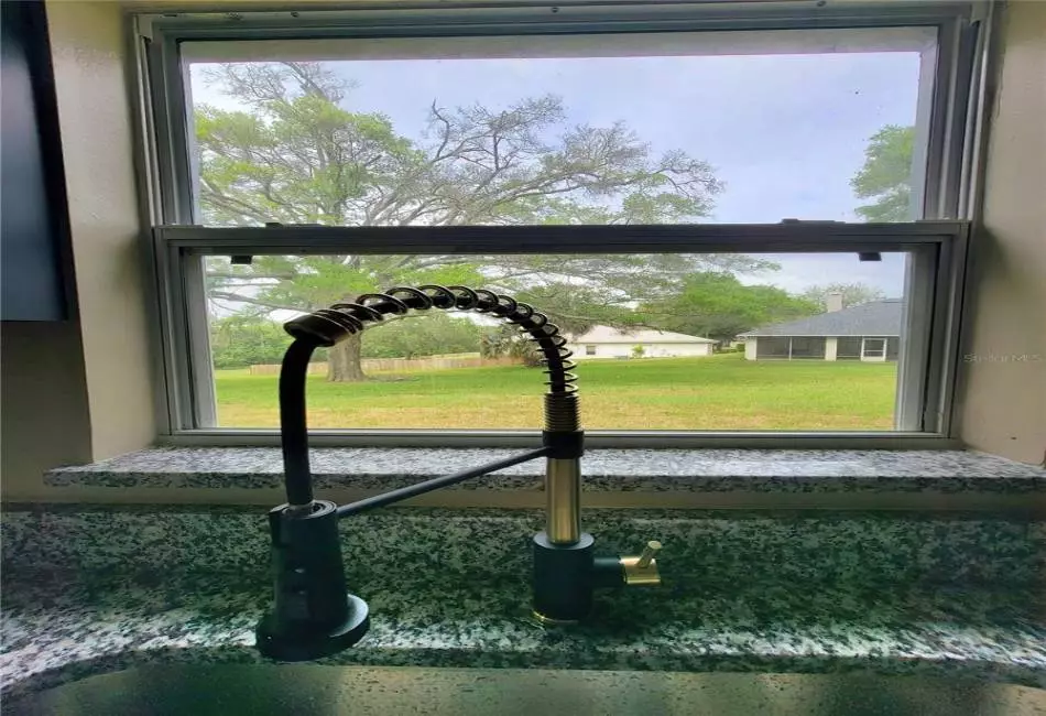 Beautiful green garden view from Farmhouse style sink. Custom Kitchen Designer Fixtures, Granite Counters.