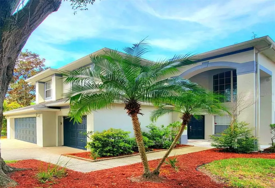Front Entryway with 3-car garage in Designer Custom Color, beautifully landscaped, palm trees.