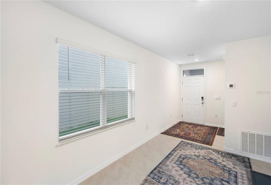 Next to the foyer/front door is a hallway that leads to the laundry room and garage; ahead is the dining area then a hall to the secondary bedrooms/bath; beyond that is the kitchen, primary suite, and living room with access to the backyard.